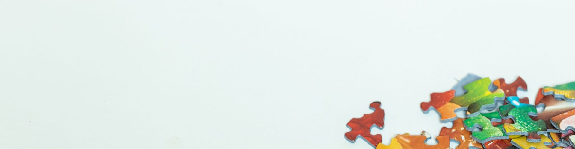 Scattered colorful puzzle pieces on a white background with copyspace.