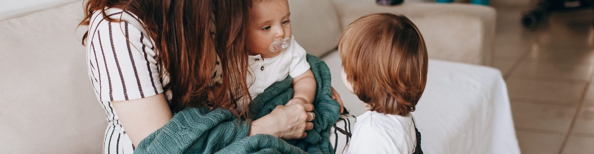 Mother and children share a warm moment on the sofa, filled with love and togetherness.