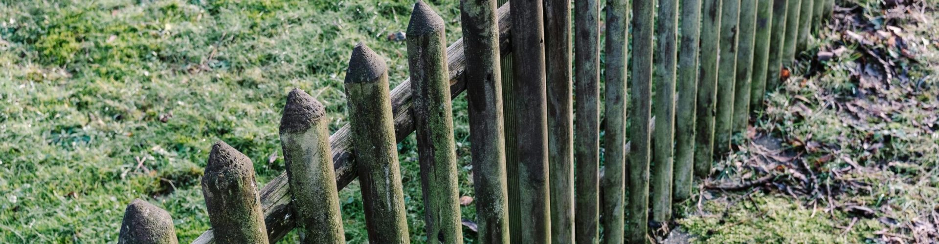 A rustic, weathered wooden fence in a grassy, outdoor garden setting. Perfect for nature photography.