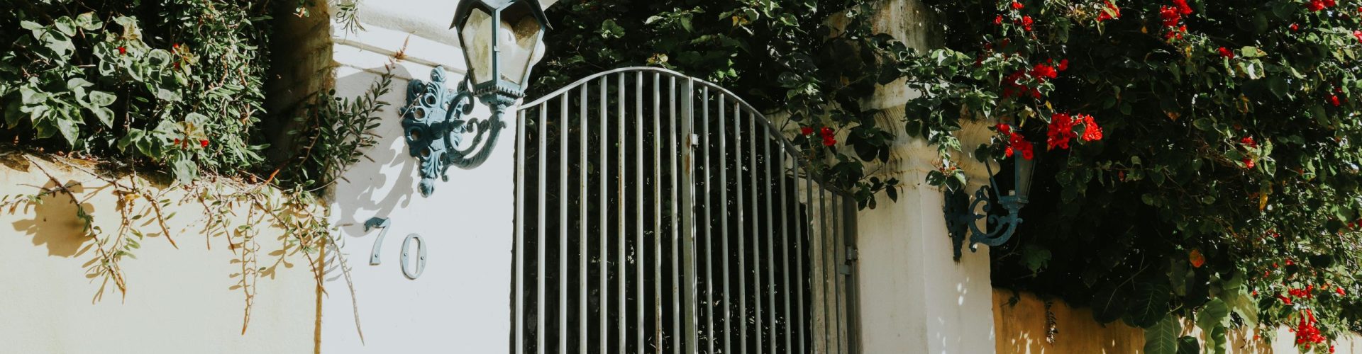 An elegant garden gate surrounded by vibrant flowers in Porto Seguro, Bahia, Brazil.
