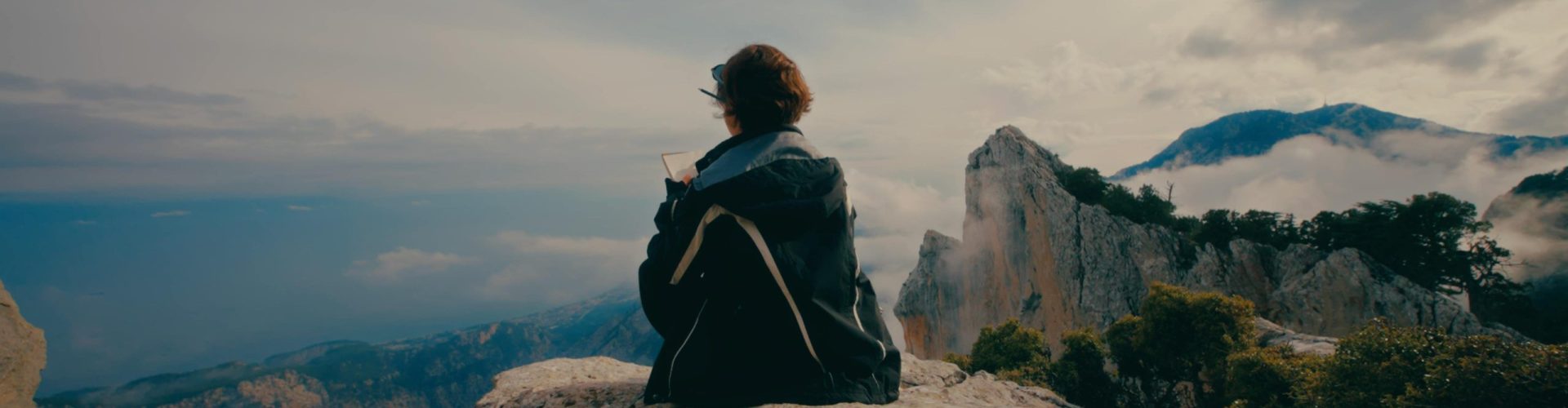 Person sitting on mountain rock enjoying the view at dusk.