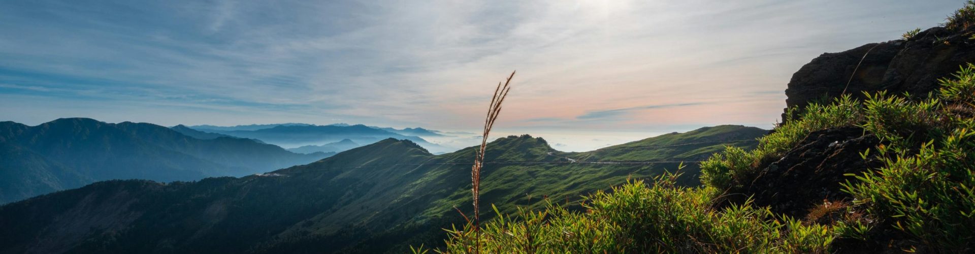 Breathtaking sunrise over lush Taiwanese mountains with expansive sky and greenery.