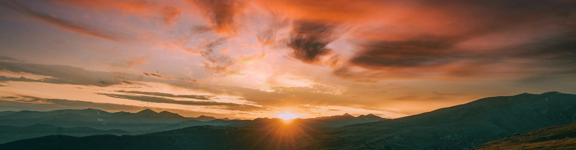 Majestic sunrise over mountain landscape with vibrant sky hues and dramatic scenery.