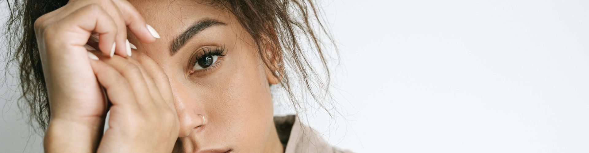 Close-up portrait of a woman with curly hair against a white background, expressing emotion.