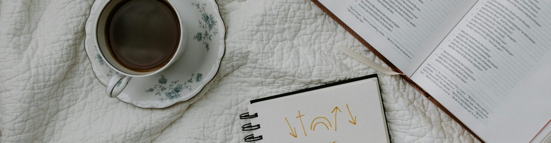 A setting of morning Bible study with coffee, notes, and a quilted fabric backdrop.